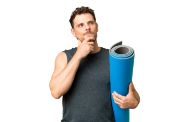 Young sport man going to yoga classes while holding a mat over isolated chroma key background and looking up