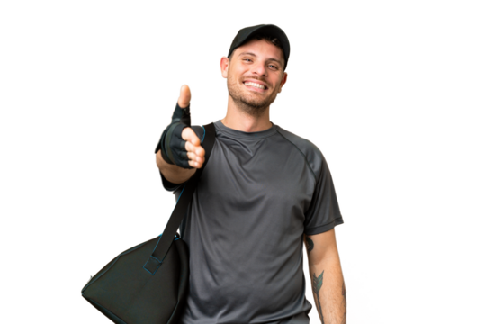 Young sport man with sport bag over isolated chroma key background shaking hands for closing a good deal