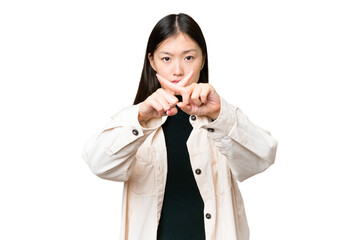 Young Asian woman over isolated chroma key background making stop gesture with her hand to stop an...