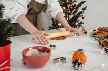 Woman preparing gingerbread cookies in the kitchen with Christmas decorations.