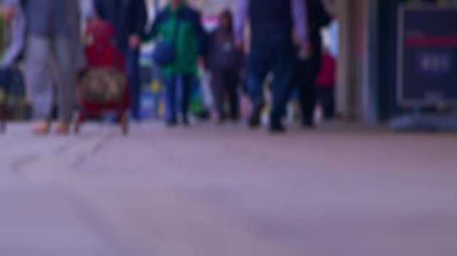 Busy city centre street with pedestrians and shoppers in bokeh. Non-specific representation of city hustle and commercial activity in the UK.