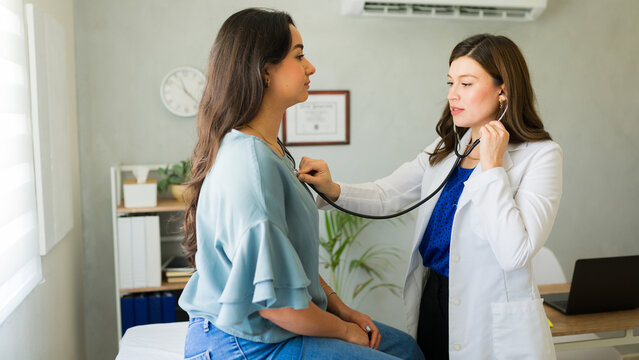 Woman doctor listens to a female patient's breathing during a medical appointment in her office