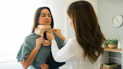 Female doctor gently applying a cervical collar to a patient with neck pain following an accident