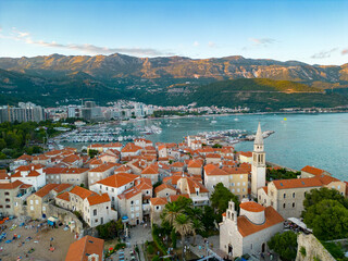 Panoramic aerial view of Budva city. Situated in Montenegro is a famous travel destination. Sunset point, warm colours on peak mountains. Porto of Budva. 