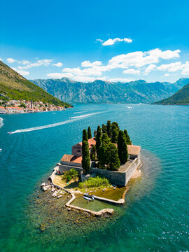 Aerial drone view of Sveti Dorde Island - Saint George Monastry in the middle of the island. In background is Perast city. Famous travel destination in Montenegro. Boats passing