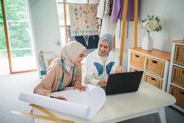 Women are actively involved in engaging in creative work using a laptop and various sketches