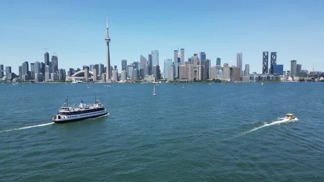 Ferry and water taxi sailing toward Toronto downtown skyline waterfront view from above Centre Island showing the entire city shoreline including the famous CN tower