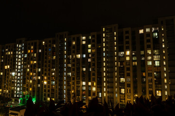 Fototapeta premium Night big city light. Multistorey residential building. The windows of the house glow in the dark. Modern architecture. Condominium