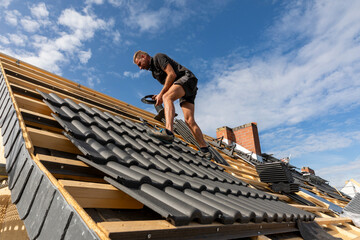 Ein Dach wird neu gedeckt. Unterkonstruktion mit Weichfaserplatten, Dachlatten, Beton-Dachsteine in...