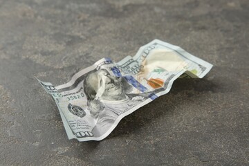 One crumpled dollar banknote on grey table, closeup