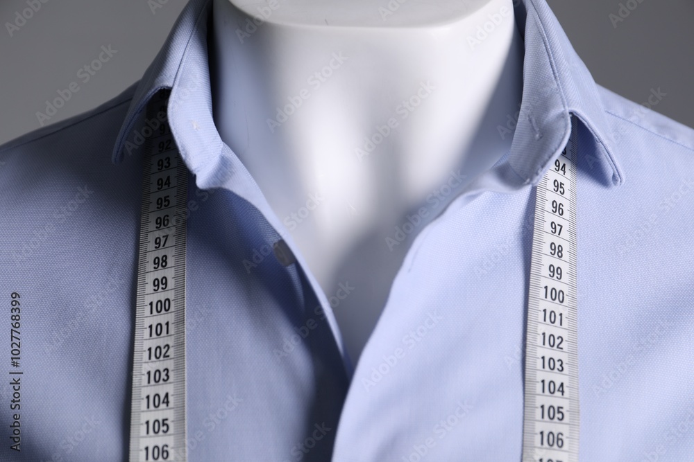 Sticker Male mannequin with light blue shirt and measuring tape on grey background, closeup