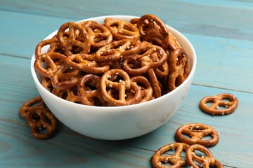 Tasty pretzel crackers on light blue wooden table, closeup