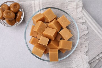 Tasty sweet caramel candies in bowls on light grey table, flat lay