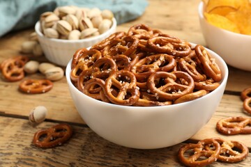 Delicious pretzel crackers and other snacks on wooden table, closeup