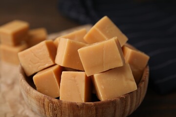 Tasty sweet caramel candies in bowl on table, closeup