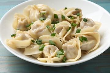 Delicious pelmeni with green onion on blue wooden table, closeup