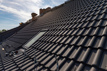 Ein Dach wird neu gedeckt. Anthrazitfarbene Beton-Dachsteine.