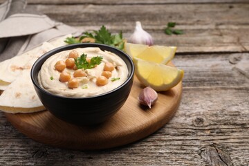 Delicious hummus with chickpeas and pita served on wooden table