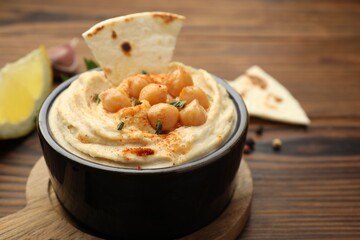 Delicious hummus with chickpeas and pita served on wooden table, closeup
