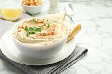 Delicious hummus with paprika and pita on white marble table, closeup