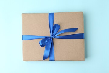 Gift box with blue bow on color background, top view