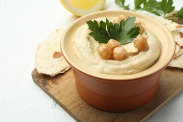 Delicious hummus with parsley, chickpeas and pita on white table, closeup