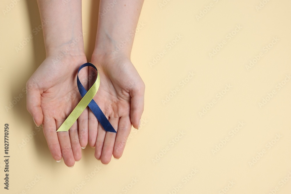 Wall mural Woman with yellow and blue ribbon on beige background, top view with space for text. Down syndrome awareness