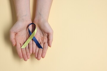Woman with yellow and blue ribbon on beige background, top view with space for text. Down syndrome...