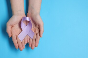 Woman with violet ribbon on light blue background, top view with space for text. Alzheimer disease,...