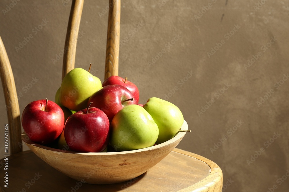 Canvas Prints Ripe red and green apples in bowl on wooden chair near grey wall. Space for text