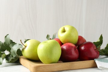 Ripe apples and green leaves on white marble table