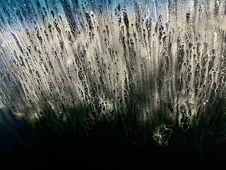 Obraz premium Close-up view of water splashes during a car wash at night, highlighting soap foam and dynamic water patterns under artificial light