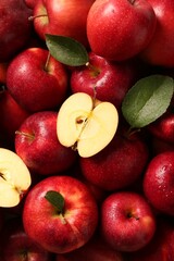 Fresh ripe red apples and green leaves as background, top view