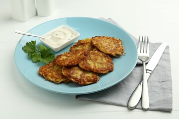 Delicious potato pancakes served on white wooden table, closeup
