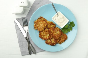Delicious potato pancakes served on white wooden table, flat lay
