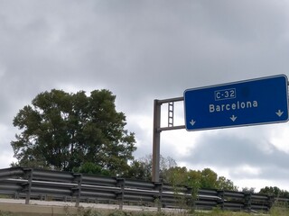 blue highway sign with the direction name Barcelona on a cloudy day © Jaume