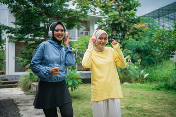 Fototapeta premium two beautiful hijab women wearing headphones during outdoor activities