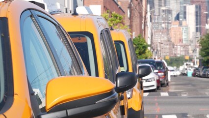 New York City. Row of yellow Taxi cars on street, Queens. Many taxi cabs on avenue, Long Island, LIC. Medallion taxicab and Manhattan Midtown urban skyline cityscape. High-rise building architecture.