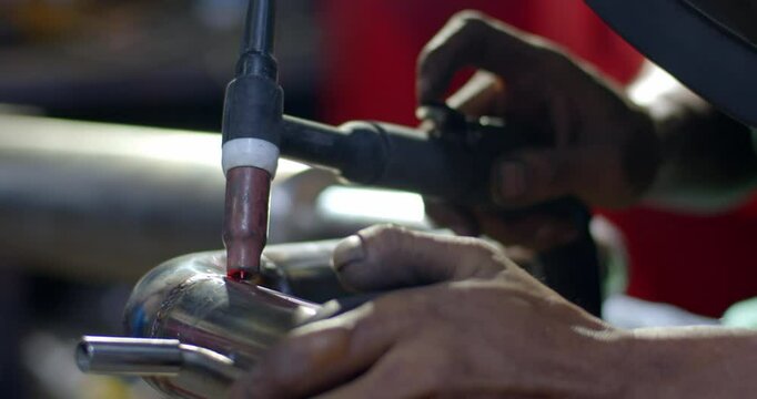 Close up tig welding.Car pipe welding.The hand of a mechanic or welder is fixing a car exhaust system.Tig welding makes the welds come out beautiful.