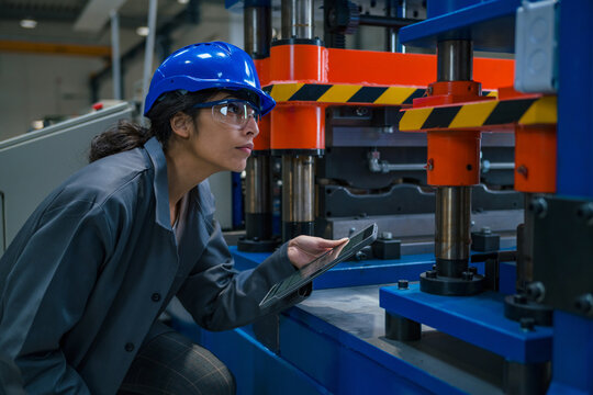 Indian woman industrial engineer, with a blue helmet and safety goggles, during a factory machinery check, close up shot. Maintenance concept. - Powered by Adobe
