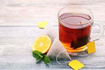 Cup of tea with tea bags, mint leafs and lemon on wooden table