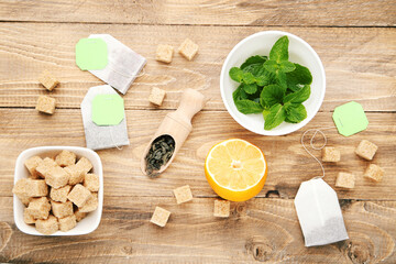 Tea bags with mint leafs, lemon and sugar cubes on brown wooden table