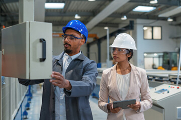 Indian female manager and African American male chief engineer walking through the factory, talking and planning production optimization, front view.