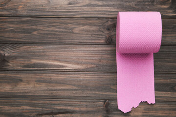 Pink roll of toilet paper on brown wooden background