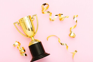 Golden trophy cup with confetti on pink background
