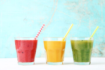 Healthy fruit and vegetable smoothies in glasses on blue background