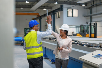 Female manager engineer giving high five to industry worker in manufacture factory.