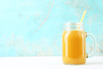Orange smoothie in glass jar on blue background