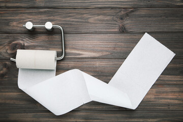 Empty roll of toilet paper hanging on chrome holder on brown wooden background