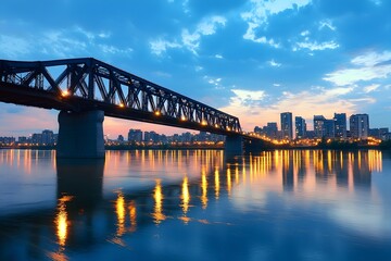 Naklejka premium Captivating Cityscape Skyline with Illuminated Bridge at Twilight Reflected on Serene River
